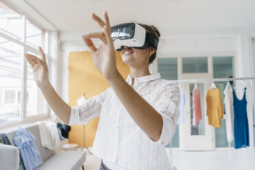 Young woman in fashion studio wearing VR glasses - KNSF02982