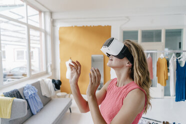 Young woman in fashion studio wearing VR glasses - KNSF02983