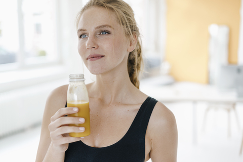 Portrait of smiling young woman in sportswear drinking a smoothie stock photo
