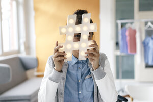 Junge Frau versteckt sich hinter Hashtag-Schild im Studio - KNSF03016