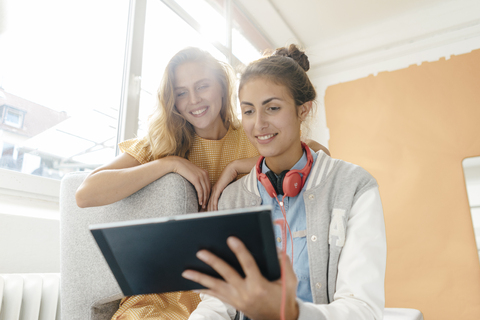 Two smiling young women using tablet stock photo