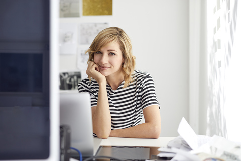 Portrait of smiling blond business woman with laptop stock photo
