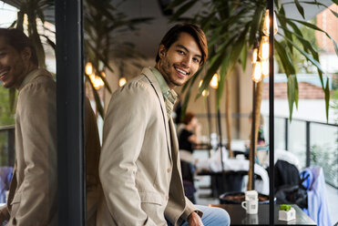 Porträt eines lächelnden jungen Mannes in einem Straßencafé - VABF01372