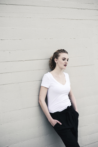 Portrait of cool young woman leaning against wall stock photo