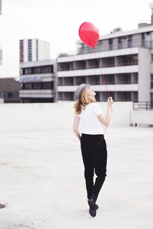 Rückenansicht einer jungen Frau mit rotem Luftballon - UUF12327