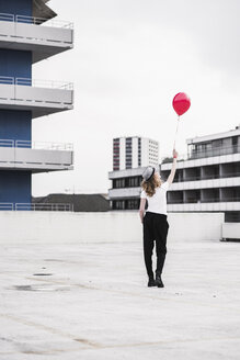 Rückenansicht einer jungen Frau mit rotem Luftballon - UUF12328