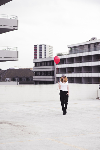 Junge Frau mit rotem Luftballon, lizenzfreies Stockfoto