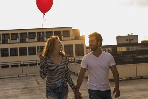 Glückliches junges Paar auf der Dachterrasse bei Sonnenuntergang - UUF12342