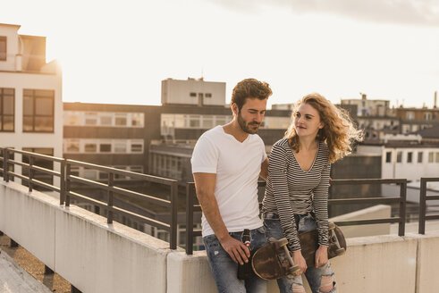 Young couple relaxing on roof terrace at sunset - UUF12350