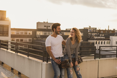 Glückliches junges Paar entspannt sich bei Sonnenuntergang auf der Dachterrasse, lizenzfreies Stockfoto