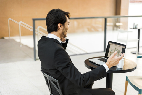 Geschäftsmann arbeitet an einem Laptop im Freien, lizenzfreies Stockfoto