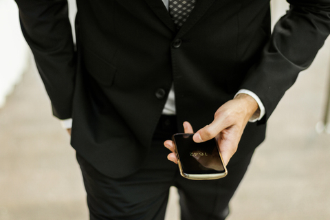 Nahaufnahme eines Geschäftsmannes, der sein Smartphone im Freien benutzt, lizenzfreies Stockfoto