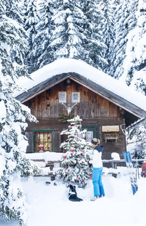 Österreich, Altenmarkt-Zauchensee, Frau schmückt Weihnachtsbaum auf Hütte - HHF05528