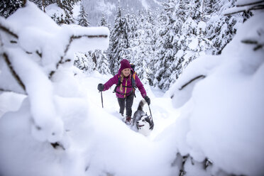 Österreich, Altenmarkt-Zauchensee, junge Frau mit Hund auf Skitour im Winterwald - HHF05534