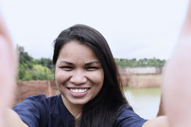 Thailand, Chiang Mai, Selbstporträt einer lächelnden jungen Frau - IGGF00197