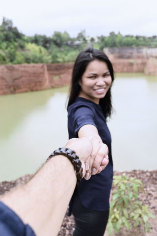 Thailand, Chiang Mai, glückliche junge Frau hält die Hand ihres Partners im Grand Canyon, lizenzfreies Stockfoto