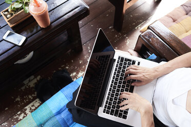 Overhead view of woman using laptop sitting on terrace bench - IGGF00211