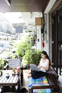 Frau mit Laptop auf einer Terrassenbank sitzend - IGGF00212