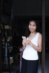 Porträt einer lächelnden Frau mit Mobiltelefon - IGGF00216