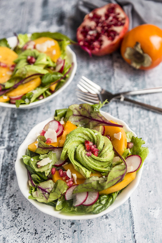 Kaki salad with red radish, pomegranate, avocado and cheese stock photo