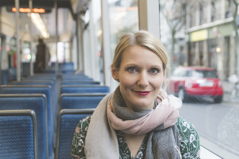Porträt einer lächelnden Frau, die in einer Straßenbahn sitzt, lizenzfreies Stockfoto