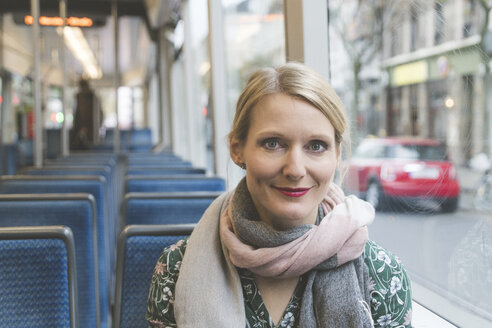 Porträt einer lächelnden Frau, die in einer Straßenbahn sitzt - CHPF00448