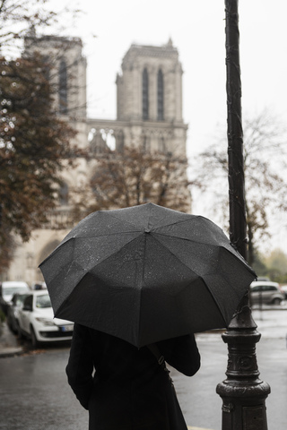 Frankreich, Paris, Frau mit Regenschirm vor der Notre Dame de Paris, lizenzfreies Stockfoto