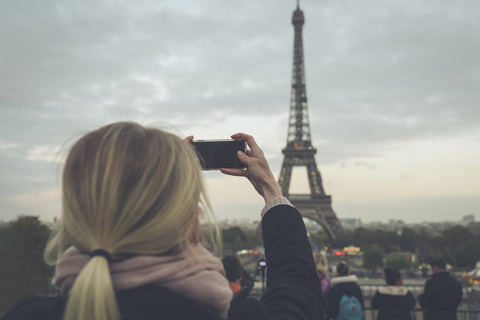 Frankreich, Paris, Eiffelturm, Frau fotografiert mit Smartphone, lizenzfreies Stockfoto