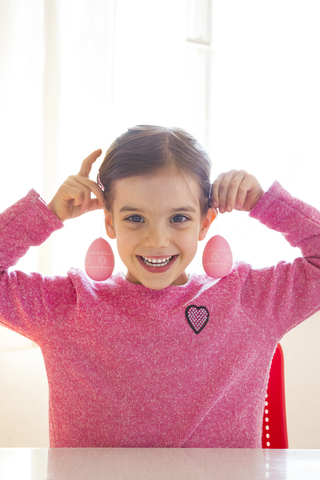 Porträt eines lachenden Mädchens mit rosa Ostereiern, lizenzfreies Stockfoto