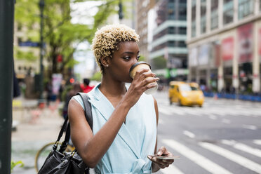 USA, New York, junge blonde afro-amerikanische Frau mit Kaffeetasse und Smartphone - MAUF01240