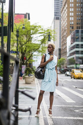 USA, New York, junge blonde afro-amerikanische Frau mit Kaffeetasse und Smartphone - MAUF01241