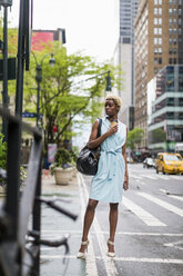 USA, New York, young blonde african-american woman with coffee mug and smart phone - MAUF01241