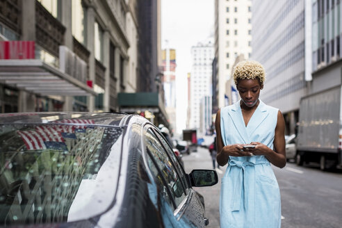 USA, New York, junge blonde afroamerikanische Frau mit Smartphone - MAUF01251