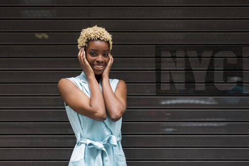 USA, New York, glückliche junge blonde afro-amerikanische Frau, lächelnd, Hand auf dem Kopf - MAUF01254