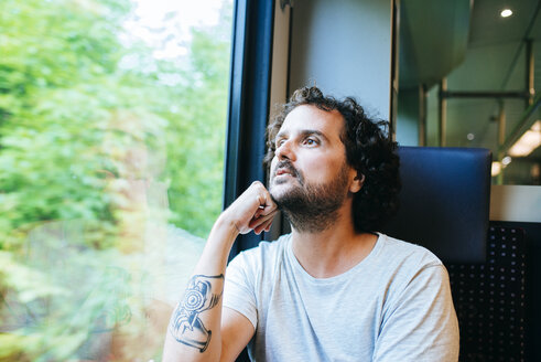 Man traveling by train looking out of window - KIJF01715