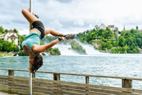 Switzerland, Schaffhausen, woman doing pole dance posture at the Rhine Falls - KIJF01716