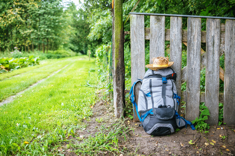 Frankreich, Straßburg, Reiserucksack und Strohhut vor einem Holzzaun auf dem Weg, lizenzfreies Stockfoto