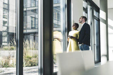 Kollegen schauen im Büro aus dem Fenster - UUF12380