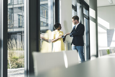 Colleagues talking at the window in office - UUF12381