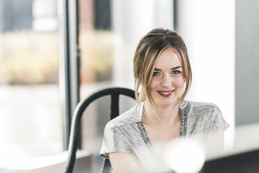 Portrait of smiling businesswoman at desk in office - UUF12401