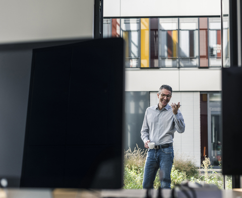 Glücklicher Geschäftsmann mit Mobiltelefon und Kaffee vor dem Büro, lizenzfreies Stockfoto