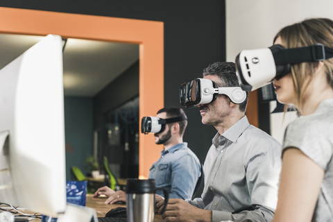 Colleagues wearing VR glasses in office stock photo