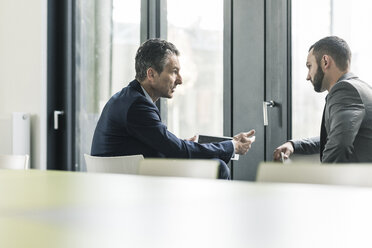 Two businessmen talking in office at the window - UUF12421