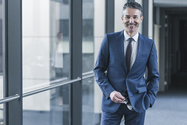 Portrait of smiling businessman on office floor - UUF12429