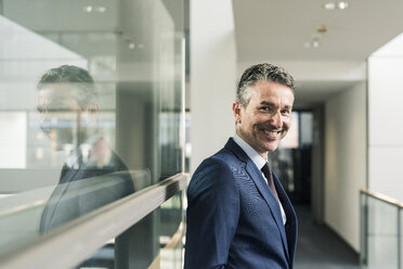 Portrait of smiling businessman on office floor - UUF12440