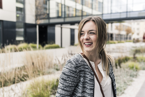 Lächelnde junge Frau vor einem Bürogebäude, lizenzfreies Stockfoto