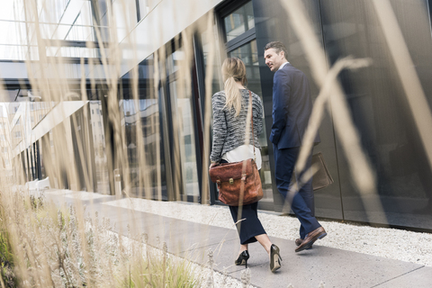 Geschäftsmann und Frau gehen vor einem Bürogebäude, lizenzfreies Stockfoto