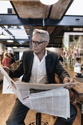 Geschäftsmann sitzt in einem Café, macht eine Pause und liest Zeitung - GUSF00178