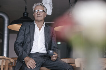 Älterer Geschäftsmann trinkt Kaffee, sitzt am Tisch - GUSF00186