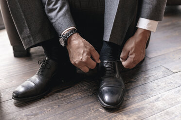 Businessman putting on shoes, tying shoelace - GUSF00187
